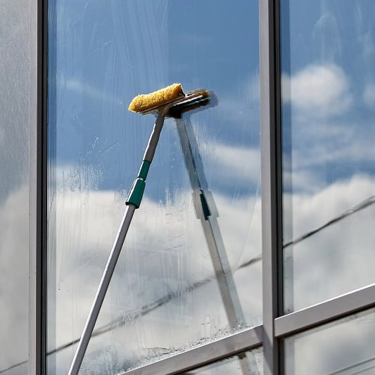 A professional cleaner washing windows on a low-rise building