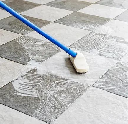 Janitor scrubbing tile floor in a commercial lobby